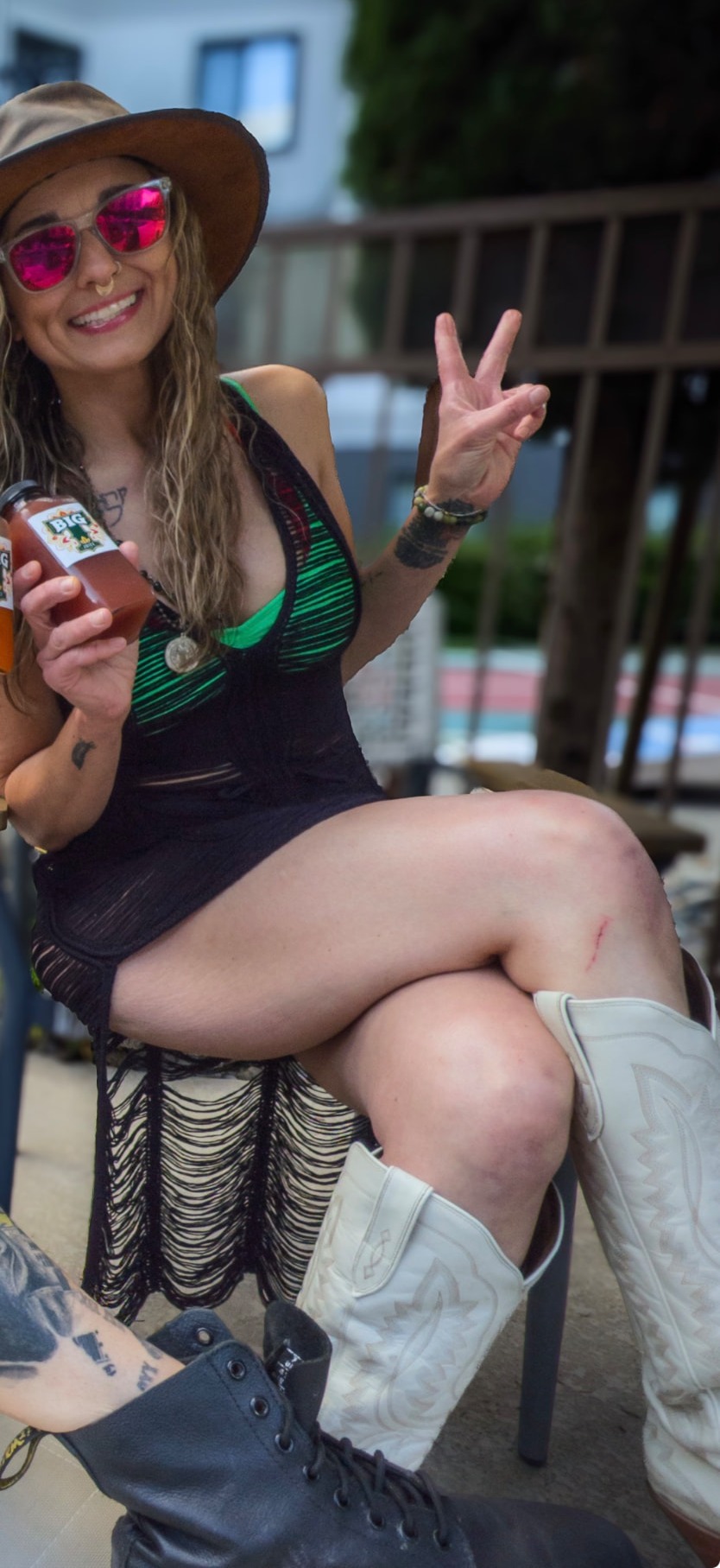 Tiffany, founder of BIG T Juice, holding a bottle of BIG T Juice and flashing a peace sign