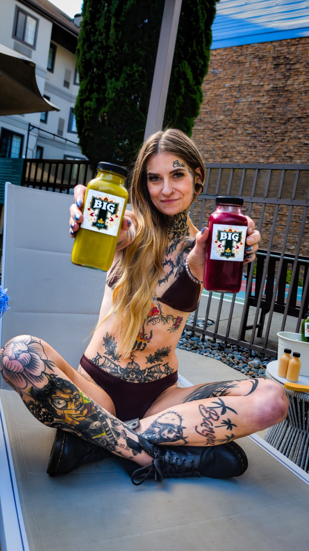 Tiffany sitting poolside and holding two colorful BIG T Juice bottles